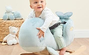 Bébé sur un jouet à bascule en figurine de baleine bleu