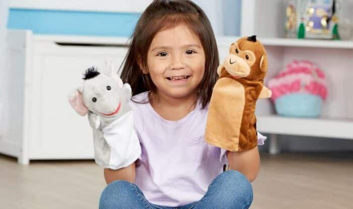 Une fille jouant avec deux marionnettes animales