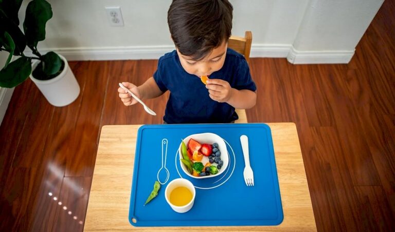 Un petit garçon qui prend son repas sur un set de table Montessori