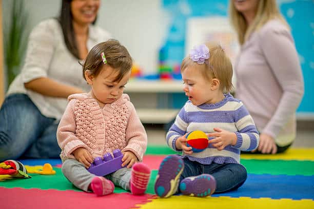Bébés de un an jouant ensemble sur le tapis dans la salle d'une crèche 
